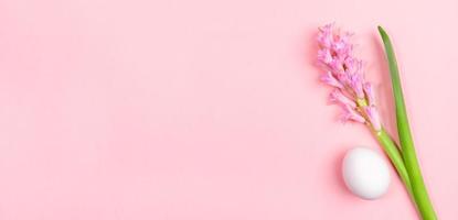 Easter minimal banner with one white egg and pink hyacinth flower on pastel pink background with copy space. photo