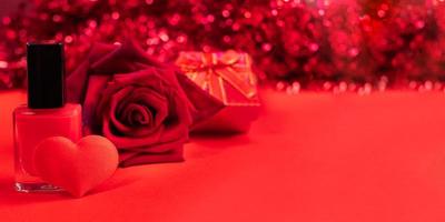 pancarta roja del día de san valentín o del día de la madre. esmalte de uñas, corazón textil, rosa, caja de regalo sobre fondo rojo con bokeh. foto