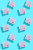 Seamless pattern of gift boxes, wrapped in grey paper with floral pattern with pink hearts and shadows on turquoise. photo