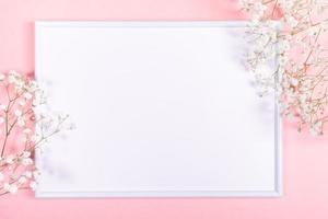 Frame with white copy space and gentle white gypsophila flowers on pastel pink. Spring festive background. photo