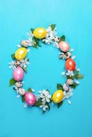 Colored hen eggs, quail eggs and white Apple tree flowers laid out as Easter egg on turquoise painted wooden background. photo
