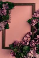 Wooden frame with branches of blooming cherry twigs or apple tree on pink with copy space. Vertical orientation. photo