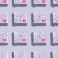 Seamless pattern of gift boxes wrapped in grey paper with floral pattern with pink hearts and shadows on grey backdrop. photo