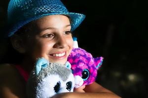 A little girl hugs her stuffed dolls photo