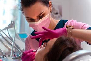 dentista con uniforme rosa trata los dientes de un paciente foto