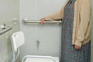 Asian elderly old woman patient use toilet support rail in bathroom, handrail safety grab bar, security in nursing hospital. photo