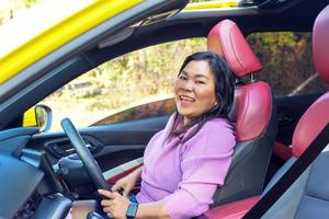 mujer asiática y automóvil con techo de bucle solar asientos de cuero rojo-negro concepto viajes, turismo, conducción. y accesorios para autos. enfoque suave y selectivo. foto