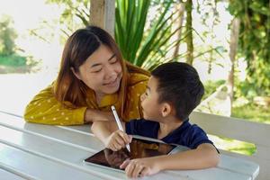 Mother teaches son to use tablet to learn online. Concept adult teaching children, family relations, family, learning outside the classroom, outside activities.soft and selective focus. photo