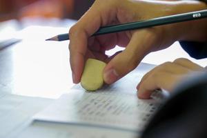 Asian student use erasers to erase wrong answers on exams to measure their knowledge in the classroom. Soft and selective focus. photo