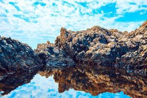 rocks and their reflection in the sea photo