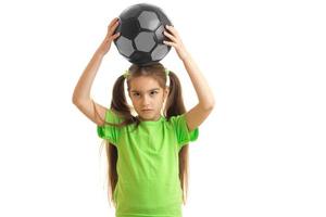niña encantadora sosteniendo un balón de fútbol en la cabeza foto
