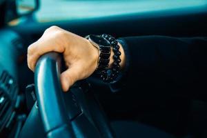 High contrast picture of male hand with watch and bracelet in car photo