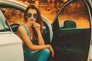 young brunette in blue sunglasses in the car photo