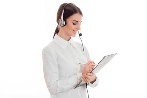 vale la pena poner de lado a una joven de camisa blanca con auriculares y escribir algo en papel foto