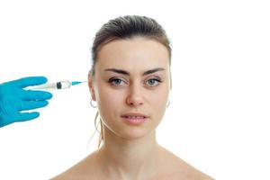 Portrait of young beautiful girls which receives an injection syringe on her face close-up photo