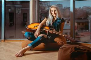 Horizontal portrait of young beautiful girl with guitar in hands photo