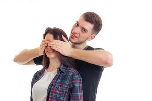 handsome young guy shuts hands girls eye and smiling photo