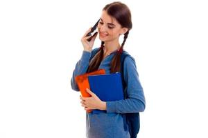 young beautiful student girl with backpack posing and talks phone isolated on white background in studio photo