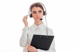 Retrato de una pensativa morena trabajadora del centro de llamadas con auriculares y micrófono aislado de fondo blanco foto