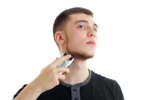 young serious guy raised his head and shaves his beard is isolated on a white background