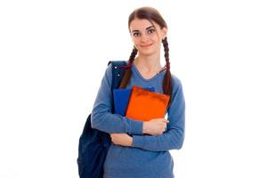 cheerful young student girl with backpack and books looking at the camera and smiling isolated on white background. student years concept. study concept. photo