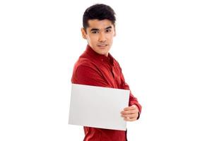 handsome young guy in red t-shirt with empty placard looking at the camera isolated on white background photo