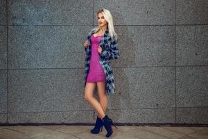 Cute young blonde fashion model in dress and coat posing outdoors photo