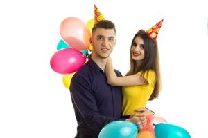young gay couple standing next to each other with large colored balloons and hats in the shape of a cone on your head photo