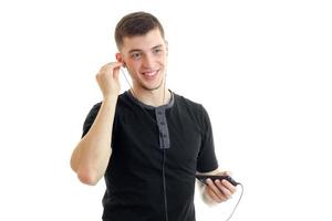 joyful handsome guy inserts earphones into your ears and listen to music from your phone photo