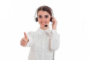 beautiful young brunette business woman with headphones and microphone showing thumbs up and smiling isolated on white background photo