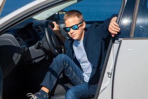 boy sits in the car in sunglasses photo