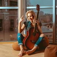 foto de mujer rubia divertida con guitarra y hermosa sonrisa