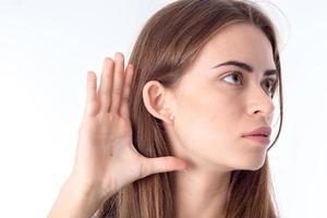 Portrait of a young girl who looks away and keeps your hand with  fingers next to  ear close-up photo