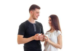 lindo chico encantador y hermosa joven sosteniendo una taza y mirándose el uno al otro foto