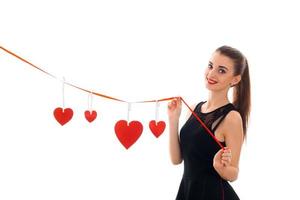 joven dama morena feliz con corazón rojo en estudio sonriendo en cámara aislada sobre fondo blanco. concepto de día de san valentín. foto