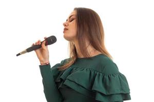 Chica joven sensual en vestido verde canta la canción en el micrófono foto
