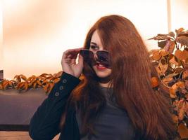 woman with red hair and sunglasses looking out of the camera photo