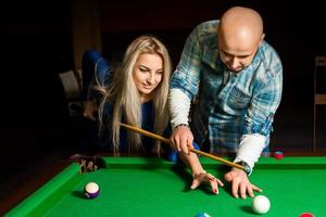 Teacher shows a girl how to play pool billiard photo