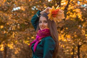 young cute girl in pink headscarf lifted his hand with the leaves above her head and smiles photo