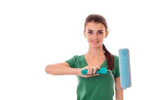 portrait of young lovely brunette building woman in uniform with paint roller in hands makes renovation and smiling on camera isolated on white background photo