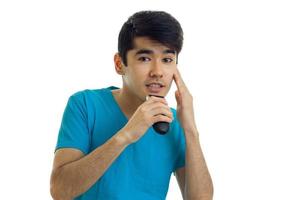 handsome young man in a blue t-shirt looks straight and shaves machine photo