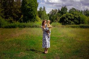 beautiful young woman walks carrying little daughter at warm summer day photo