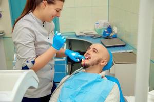 Linda mujer dentista revisa los dientes de su paciente en el consultorio dental foto