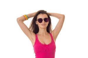 young fashionable brunette girl in pink sunglasses and shirt posing on camera isolated on white background photo