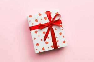 Background with gift box and hearts on rose Background. Top view with copy space for text photo