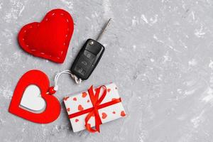 Top view of a present for Valentine's Day on wooden background. Car key, gift box and heart with copy space. Surprise concept for a holiday photo