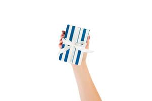 las manos de las mujeres dan Navidad envuelta u otro regalo hecho a mano en papel azul con cinta blanca. aislado sobre fondo blanco, vista superior. concepto de caja de regalo de acción de gracias foto