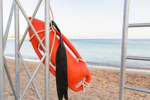 torre de salvavidas con boya naranja en la playa. boya de rescate en el puesto de rescate de hierro foto