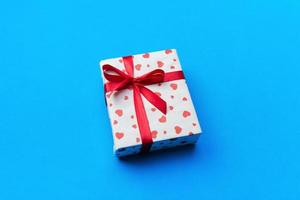 Background with gift box and hearts on blue Background. Top view with copy space for text photo