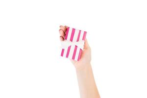 Woman hands give wrapped Christmas or other holiday handmade present in pink paper with white ribbon. Isolated on white background, top view. thanksgiving Gift box concept photo